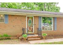 Charming brick home entrance with decorative door, blue shutters and flower urns at 504 Amon Ln, Pineville, NC 28134
