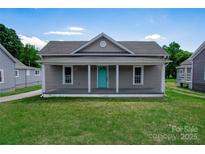 Charming home with a large, well-manicured lawn and a welcoming covered porch at 921 W 1St St, Lowell, NC 28098