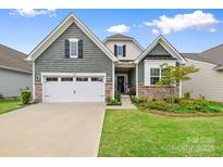 Charming home boasts a two-car garage, landscaped lawn, and stylish green siding with stone accents at 12637 Belmont Mansion Dr, Charlotte, NC 28273