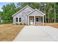 Charming one-story home with gray siding, a new concrete driveway and a well-manicured lawn at 213 E Division Ave, Salisbury, NC 28144