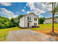 Beautiful white two-story home featuring a gravel driveway and surrounded by lush trees at 415 Kickapoo Ave, Gastonia, NC 28056