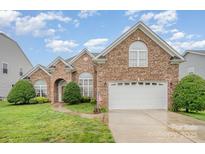 Charming brick home with well-maintained lawn, arched windows, and a two-car garage at 5052 Ashley Pl, Bessemer City, NC 28016