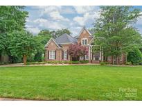 Charming two-story brick home with a manicured lawn and mature trees, exudes curb appeal at 7018 Dowington Dr, Charlotte, NC 28277