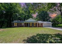 Charming brick home featuring a well-manicured lawn and inviting front porch with classic white columns at 114 Elmwood Dr, Salisbury, NC 28147