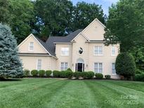 Traditional home featuring manicured lawn, lush landscaping, and charming architectural details at 12711 Duncourtney Ln, Charlotte, NC 28277