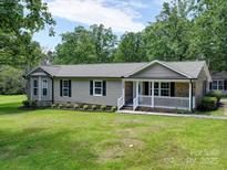 Well-maintained home with inviting front porch and lush landscaping, nestled among mature trees at 1306 Abbey Ct, Lancaster, SC 29720