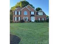 Beautiful two-story red brick home featuring a manicured lawn and classic architectural details at 15737 Agincourt Dr, Huntersville, NC 28078