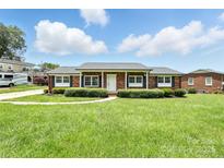 Charming brick ranch home with a well-manicured lawn and black shutters offers great curb appeal at 1735 Hollandale Dr, Gastonia, NC 28054