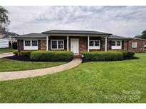 Charming brick home with well-maintained landscaping, walkway, dark shutters, and a welcoming front entrance at 1735 Hollandale Dr, Gastonia, NC 28054