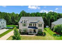Elegant two-story brick home with a beautifully landscaped front yard, dormer windows, and a covered porch at 319 S San Agustin Dr, Mooresville, NC 28117
