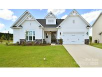 Charming single-story home featuring a manicured lawn, stone accents, and an attached two-car garage at 3924 Dahlia Dr, Harrisburg, NC 28075