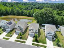 An aerial view of several homes, a pond, and a treeline on a sunny day at 461 Misty Law Ln, Clover, SC 29710