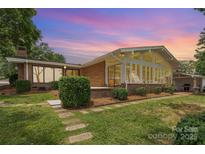 Brick home features a sunroom addition, lush landscaping, and a beautiful yard at 5114 Leisure Ln, Sherrills Ford, NC 28673