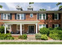 Charming brick townhouse with a welcoming front porch, complemented by black shutters and lush greenery at 524 Hawthorne Ln, Charlotte, NC 28204