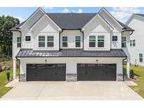 Modern home featuring white siding, a dark roof, black garage doors, and stone accents at 6032 Corbin Woods Ct, Charlotte, NC 28226
