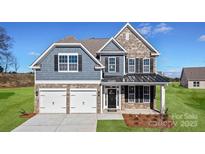 Beautiful two-story home boasts a stone and blue shingle exterior, attached two-car garage, and manicured lawn at 7101 Butternut Oak Ter, Huntersville, NC 28078