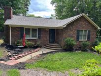 Charming brick home featuring a manicured front yard, walkway, and cozy outdoor seating area at 7316 Truelight Church Rd, Mint Hill, NC 28227