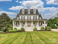 Stunning two-story home featuring a welcoming front porch, manicured lawn, and beautifully landscaped front yard at 735 Davidson Run Ln, Davidson, NC 28036