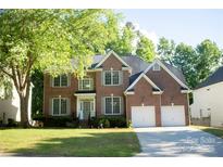 Traditional two-story brick home featuring an attached two-car garage and well-maintained landscaping at 7708 Harrington Woods Rd, Charlotte, NC 28269