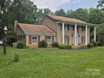 Charming two-story brick home with white pillars, red shutters, and a well-manicured lawn at 9225 Robinson Church Rd, Charlotte, NC 28215