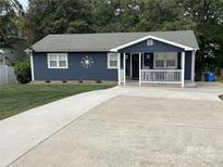 Charming single-story home featuring blue siding, a concrete driveway, and a welcoming front porch with rocking chairs at 132 Marina Ln, Mooresville, NC 28117