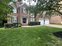 Beautiful brick home featuring a well manicured lawn, dark shutters, and a two car garage at 405 Deer Brush Ln, Waxhaw, NC 28173