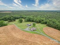 Stunning aerial view of property featuring a pond, two homes, multiple outbuildings and surrounding farmland and woods at 4115 Jenkins Rd, Marshville, NC 28103