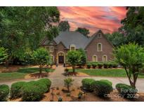 Beautiful brick home featuring a well-manicured lawn and a picturesque landscape, with a cloudy orange and pink sky at 4323 Rosecliff Dr, Charlotte, NC 28277