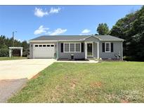 Charming one-story home features a well-manicured lawn, gray siding, and a two-car garage at 5323 Flat Creek Rd, Heath Springs, SC 29058