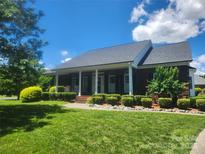 Charming brick home featuring a covered front porch and meticulously landscaped front yard with manicured bushes at 7189 Bovine Ln # 28, Harrisburg, NC 28075