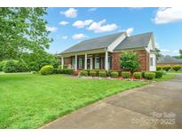 Charming brick home with a lush, landscaped front yard and inviting covered porch at 7189 Bovine Ln # 28, Harrisburg, NC 28075