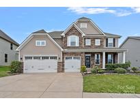 Charming two-story home with a three car garage, stone accents, a manicured lawn and covered front porch at 7339 Millstone Sw Cir, Concord, NC 28025