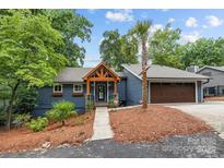 Charming blue home with a welcoming wood porch, beautiful landscaping, and a brown two-car garage at 1111 Palmyra Dr, Fort Mill, SC 29708