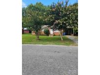 A single-story brick home with a well-kept lawn and mature trees in a serene, tree-lined neighborhood at 120 Booker St, Wingate, NC 28112