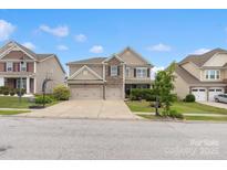 Charming two-story home featuring a stone facade, well-manicured lawn, and a spacious three-car driveway at 1810 Kerwick Ct, Lancaster, SC 29720