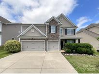 Charming two-story home with stone accents and a three-car garage, complemented by a well-manicured lawn and landscaping at 1810 Kerwick Ct, Lancaster, SC 29720