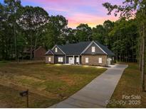 Charming single-story home featuring a stone and gray facade with a welcoming front yard and long driveway at 209 Stafford Estates Dr, Salisbury, NC 28146