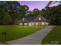 Charming single-story home featuring a well-manicured lawn and inviting stone and siding exterior at 209 Stafford Estates Dr, Salisbury, NC 28146