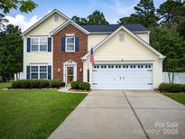 Inviting two-story home featuring yellow siding, brick accents, blue shutters and a well-manicured front yard at 4113 Edgeview Dr, Indian Trail, NC 28079