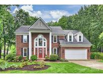 Charming brick two-story home with a red front door, manicured lawn, and lush landscaping at 6722 Elmstone Dr, Charlotte, NC 28277