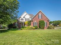 Charming brick home with manicured lawn, mature trees, and traditional architectural details under a bright blue sky at 725 Old State Sw St, Concord, NC 28027