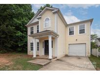 Charming two-story home with a welcoming entrance, attached garage and light yellow siding at 8432 Spirea Ct, Charlotte, NC 28215