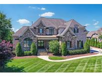 Stunning two-story home featuring a stone and brick facade, manicured lawn, and lush landscaping at 9807 Aristides Dr, Waxhaw, NC 28173