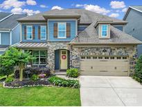 Charming two-story home with a stone facade, blue siding, manicured landscaping, and an attached two-car garage at 998 Emory Ln, Fort Mill, SC 29708