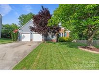 Charming home featuring a well-manicured lawn, mature trees and an attached two-car garage at 1310 Bellhook Nw Pl, Concord, NC 28027