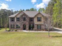 Beautiful two-story brick and stone home boasts lush lawn, mature trees, and inviting curb appeal at 240 Bells Crossing Dr, Mooresville, NC 28117