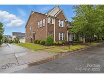 Charming brick townhome featuring manicured landscaping, lush green lawns, and mature trees at 3013 Coventry Commons Dr, Mint Hill, NC 28227
