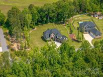 Expansive aerial view of a beautiful brick home with lush green lawns and mature trees on a private lot at 4143 Willow Haven Dr, Denver, NC 28037