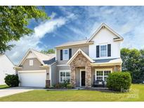 Charming two-story home with a stone porch and a well-manicured lawn under a beautiful blue sky at 4683 Dunberry Sw Pl, Concord, NC 28027
