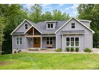 Charming grey two-story home with a wooden door, front porch swing, and a well-manicured lawn at 5215 Star Magnolia Ct, Clover, SC 29710